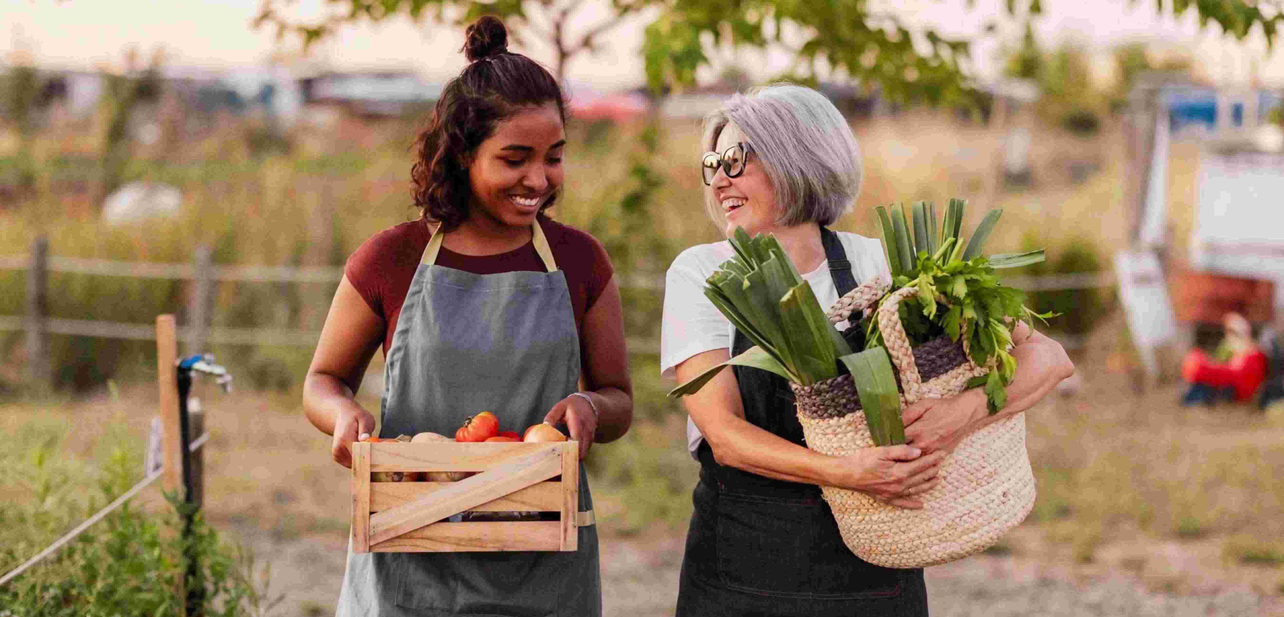 Two women holding produce from a farmer's market.