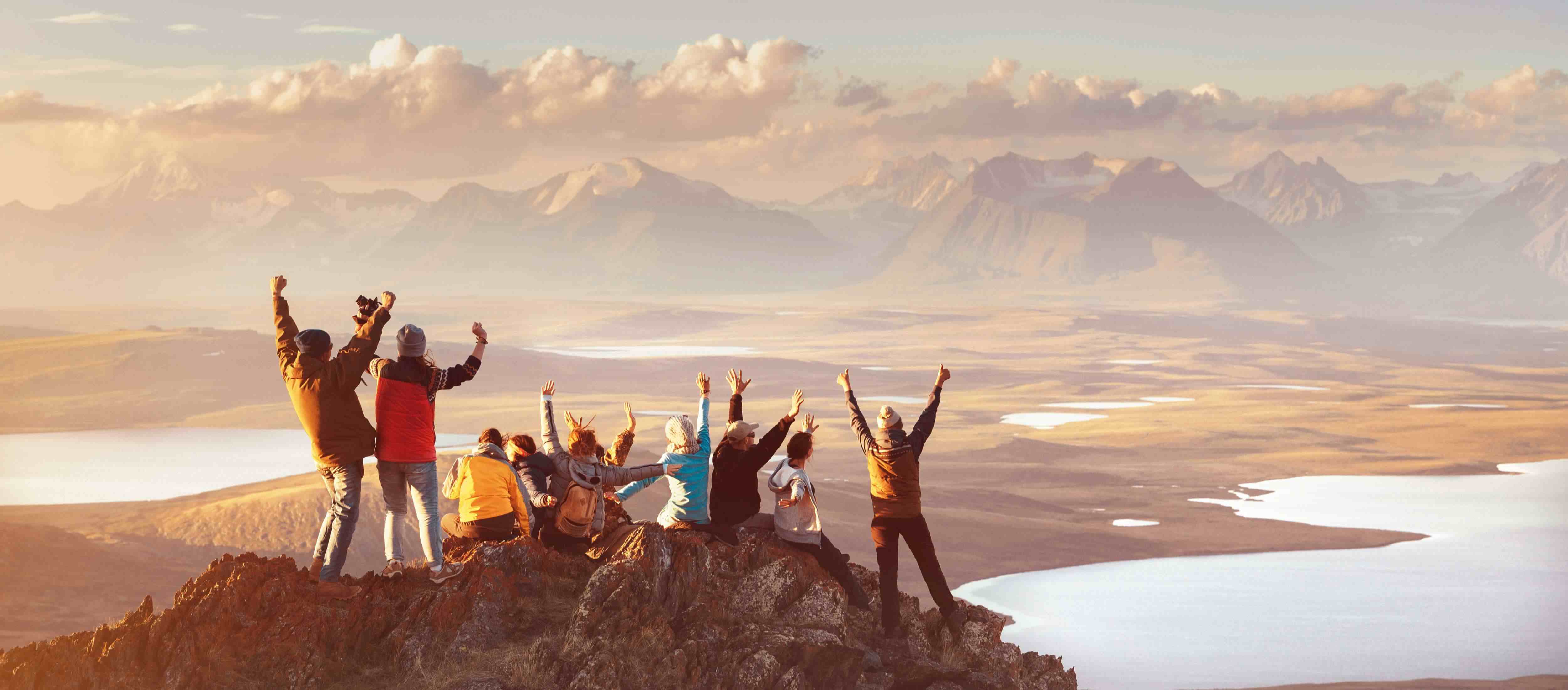Group of people celebrating on a mountain top with scenic landscape